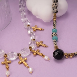 Collier en perles de jaspe dalmatien avec croix et perles bleues sur fond violet doux