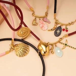 Dettaglio di collane in cuoio stile boho con vari ciondoli d'oro e pietre preziose