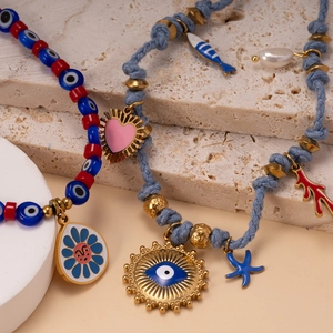 Bohemian evil eye and sunflower beaded necklace with charms on minimalist stone background