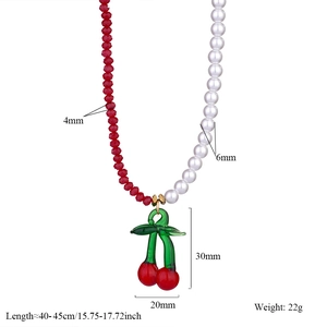 Detail of necklace with red faceted beads, white pearls and cherry pendant