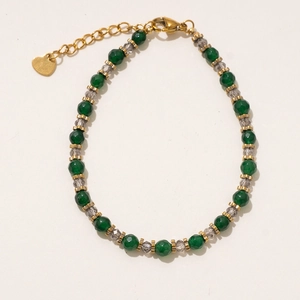 Gros plan sur les perles vertes et le pendentif cœur doré d'un collier vintage