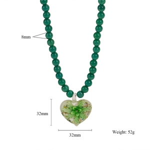 Détail des perles vertes de 8mm et d'un pendentif cœur en verre fleuri de 32mm sur collier