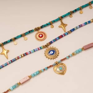 Beaded necklaces with evil eye and star pendants on a warm beige background