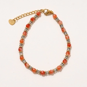Détail du collier perlé avec facettes oranges, breloque cœur doré et fermoir mousqueton réglable
