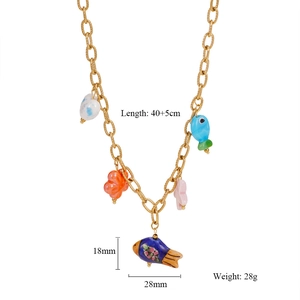 Macro shot of gold chain necklace with colorful fish and floral charms in ocean style