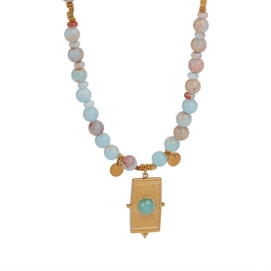 Détail du collier de perles bohème avec pendentif doré gravé d'un soleil