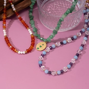Three beaded necklaces with agate, crystals and gold pendants on a lavender background