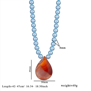 Détail du collier de perles bleues 8mm avec un pendentif goutte en agate rouge