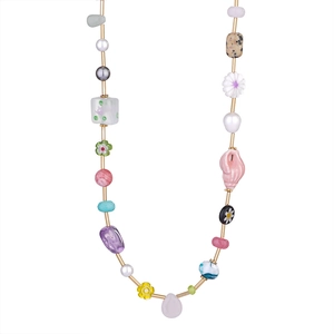 Dettaglio di collana bohemian con perle colorate e ciondolo a fiore su sfondo bianco