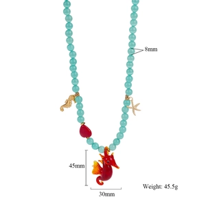 Detail of beaded necklace with blue stones, golden sea star and large red seahorse pendant