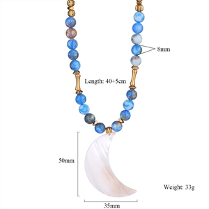Detail view of natural stone necklace with a large white crescent moon shell pendant