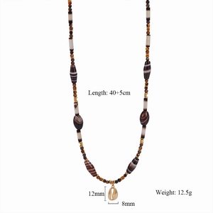 Detailed view of handmade beaded necklace with brown stones and gold shell pendant