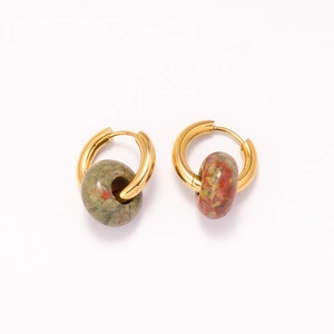 Macro detail of 18k gold earrings with natural green stone beads and unique red textures