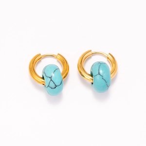 Close-up of 18k gold earrings featuring cylindrical turquoise beads with natural texture