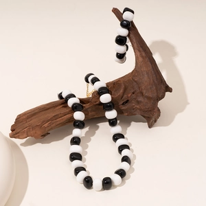 Ensemble collier et bracelet en perles noires et blanches sur support bois naturel