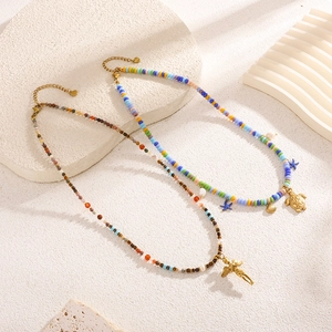 Bohemian beaded necklaces with gold angel and turtle pendants on cream textured background