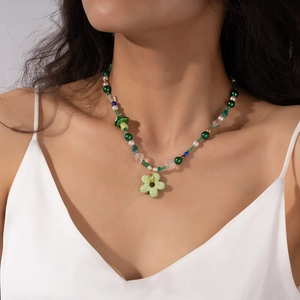 Detail of beaded necklace with green flower charm and small mushroom pendant for summer