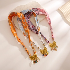 Silk scarf necklace with summer-themed fish and fruit charms on textured stone