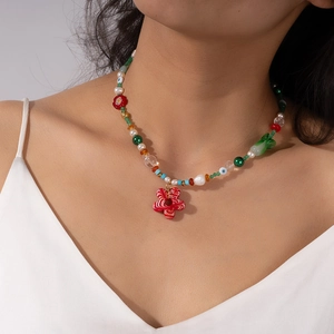 Close-up of colorful summer beaded necklace with red floral glass pendant on a model