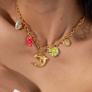 Collana a catena dorata con ciondoli a conchiglia, pesce e fiori indossata sul collo