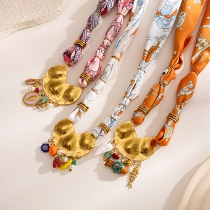 Detail of colorful silk scarves with bohemian gold fish and fruit metal pendants