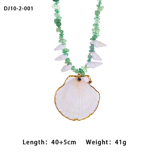 Detail of beaded necklace featuring white shell pendant and green natural stones