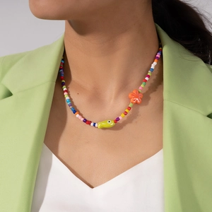 Macro shot of colorful beaded necklace with green fish charm and orange flower detail