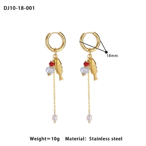 Detail of golden stainless steel hoop earrings with fish charm and colorful beads