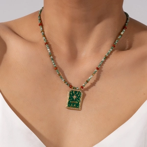 Vintage-Perlenkette in Grün mit goldenem 'LUCKY'-Anhänger an einem Model getragen