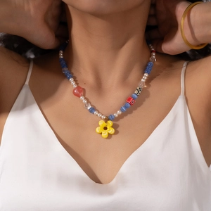 Detail of colorful beaded necklace with red heart pendant and yellow flower charm