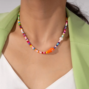 Close-up of colorful beaded necklace with small orange fish charm and white pearl