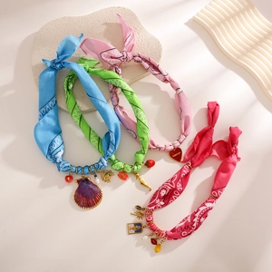 Detail of colorful paisley silk scarves with gold charms like shell, heart, and crab