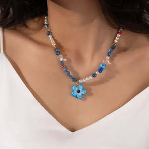 Detail of colorful beaded necklace with blue glass flower pendant and evil eye beads