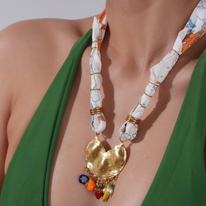 Detail of silk scarf necklace with golden hammered pendant and colorful fruit charms