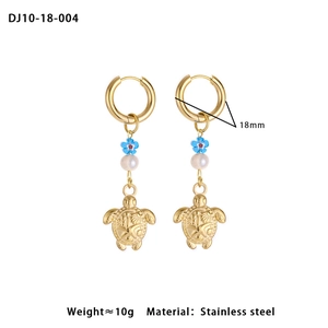 Detail of golden stainless steel turtle hoop earrings with blue enamel flower and pearl