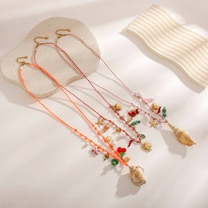 Détail de chaînes de corps bohèmes avec coquillages, pendentifs et perles colorées