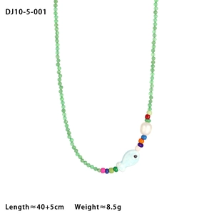 Détail d'un collier de perles en céramique avec perle blanche et breloque poisson bleu