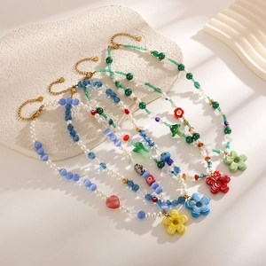 Colorful handmade beaded necklaces with mixed charms like flowers and hearts on white stone