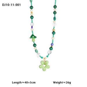 Macro shot of green beaded necklace with mushroom, flower and evil eye charms