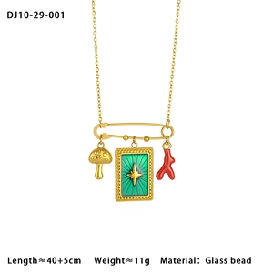Detail of gold chain necklace with mushroom, green star plaque and red coral pendants