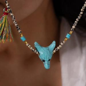 Dettaglio di collana etnica con perline, pendente a testa di volpe turchese e nappe colorate