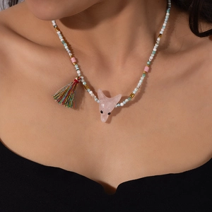 Dettaglio della collana bohémien con pendente a testa di volpe rosa e nappe colorate