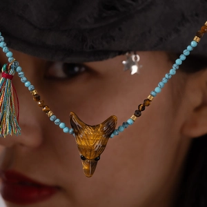 Collana bohémien con testa di lupo in occhio di tigre, perline turchesi e nappa