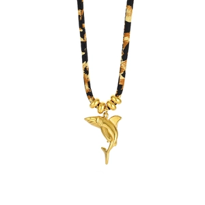Macro detail of golden shark pendant with leopard print cord and decorative beads