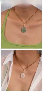 Détail macro de pendentifs en jade en forme de conque avec zircons et chaînes dorées