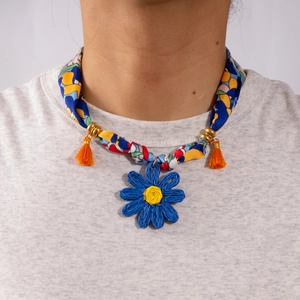 Close-up of ethnic braided daisy pendant with blue and yellow floral fabric necklace