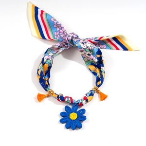 Detail of colorful silk scarf necklace with golden beads and a blue knit daisy charm