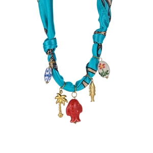 Detail of silk scarf necklace featuring blue fabric with tropical palm and fish charms
