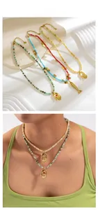 Gros plan de colliers de perles colorées avec pendentifs Hamsa sur une surface en pierre