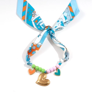 Macro shot of blue floral silk scarf necklace with colorful resin beads and gold heart charms